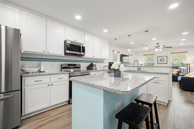 607 Huisache Lane, Ingleside On The Bay, TX 78362 - kitchen featuring stainless steel appliances, a sink, a peninsula, light wood-style flooring, and recessed lighting