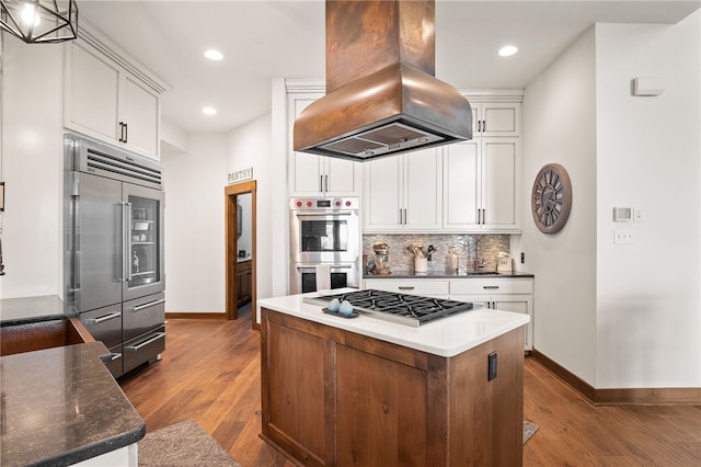 5502 E Riverview Dr, Corpus Christi, TX 78410 - kitchen with appliances with stainless steel finishes, island range hood, wood finished floors, tasteful backsplash, and recessed lighting