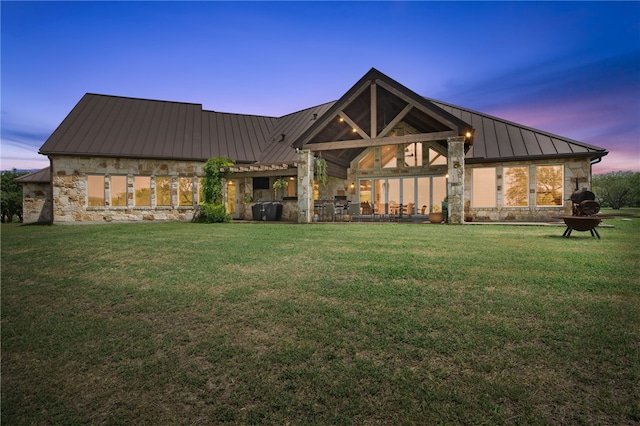 5502 E Riverview Dr, Corpus Christi, TX 78410 - rear view of property with a standing seam roof, stone siding, a metal roof, and a lawn