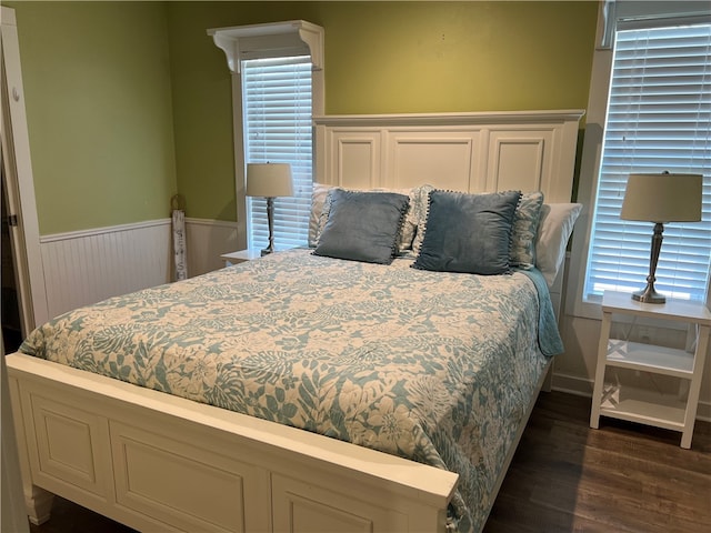 bedroom with multiple windows and dark hardwood / wood-style floors