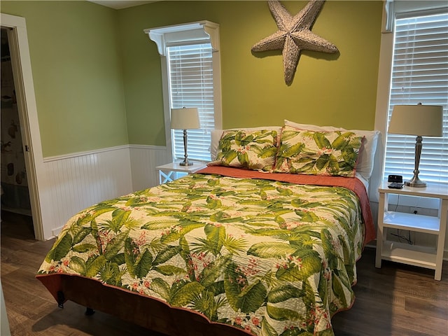 bedroom with dark hardwood / wood-style floors and multiple windows