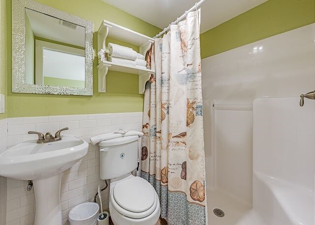 bathroom featuring tile walls, sink, toilet, and a shower with curtain