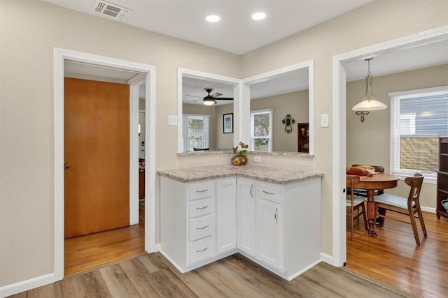 934 Cunningham St, Corpus Christi, TX 78411 - kitchen featuring light wood finished floors, white cabinets, ceiling fan, decorative light fixtures, and light stone counters