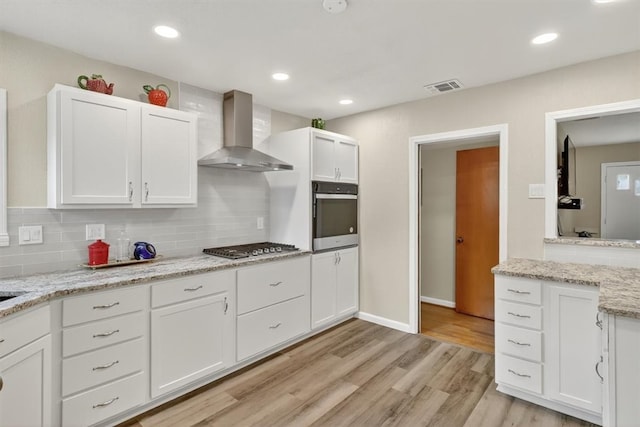 934 Cunningham St, Corpus Christi, TX 78411 - kitchen featuring wall chimney range hood, appliances with stainless steel finishes, white cabinets, light wood-type flooring, and recessed lighting