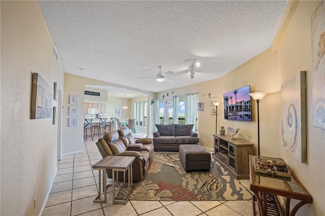 living room featuring track lighting, a textured ceiling, light tile patterned floors, and ceiling fan