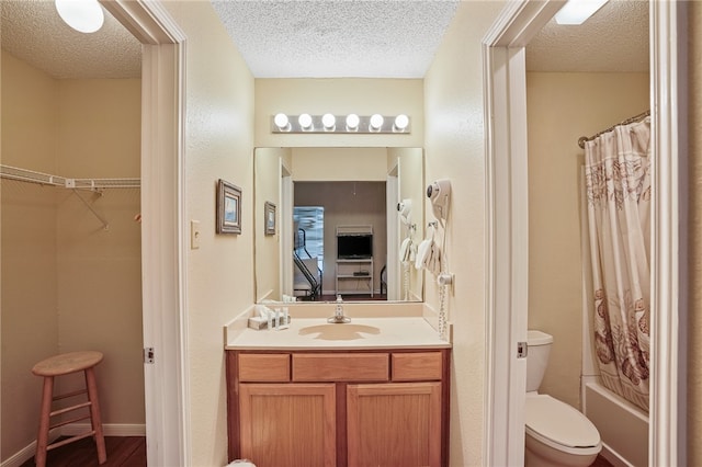 full bathroom featuring vanity, a textured ceiling, toilet, and shower / tub combo