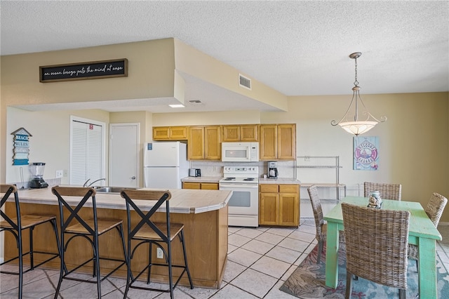 kitchen with pendant lighting, white appliances, a textured ceiling, and light tile patterned floors