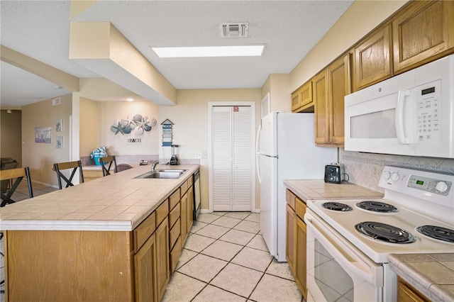 kitchen with tile countertops, light tile patterned flooring, sink, backsplash, and white appliances