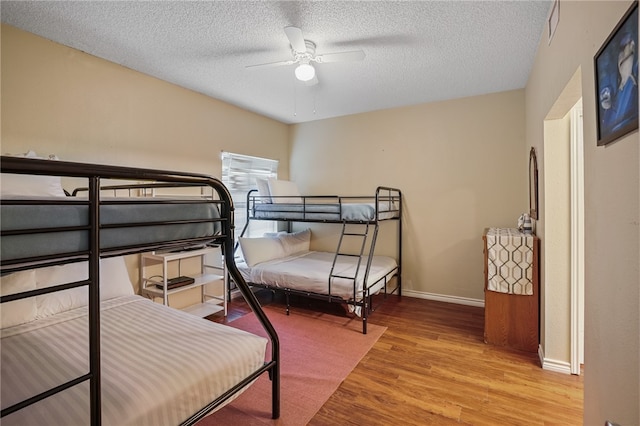 bedroom featuring light hardwood / wood-style floors, ceiling fan, and a textured ceiling