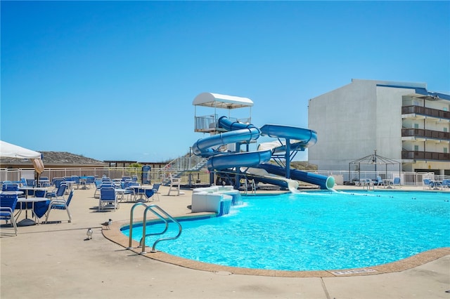 view of pool with a water slide and a patio area