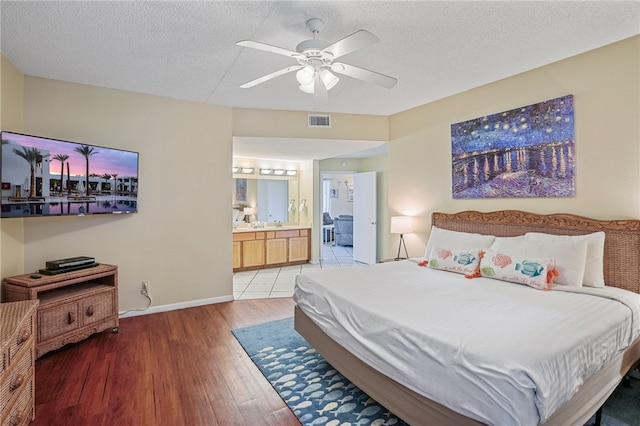 bedroom with a textured ceiling, hardwood / wood-style floors, ceiling fan, and ensuite bathroom