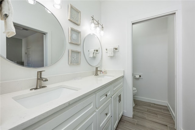 bathroom with hardwood / wood-style floors, vanity, and toilet