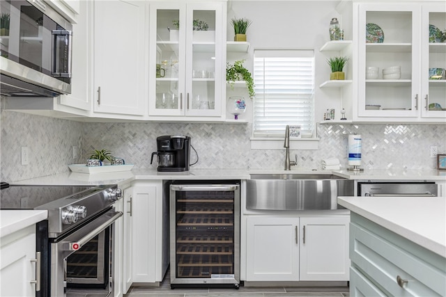 kitchen featuring appliances with stainless steel finishes, wine cooler, tasteful backsplash, sink, and white cabinetry