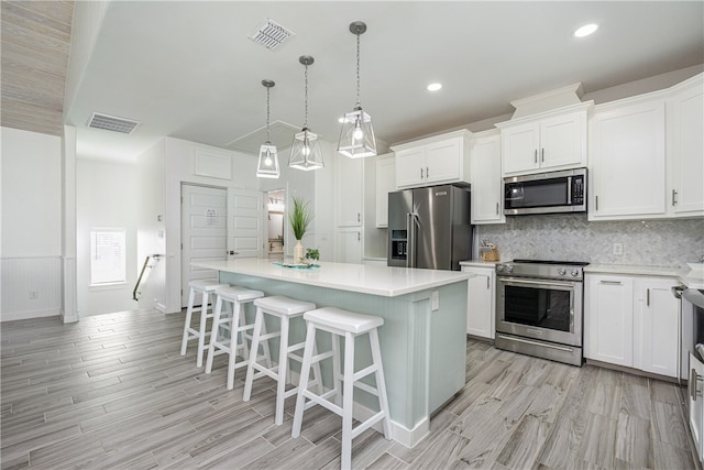 kitchen featuring white cabinetry, a center island, hanging light fixtures, and appliances with stainless steel finishes