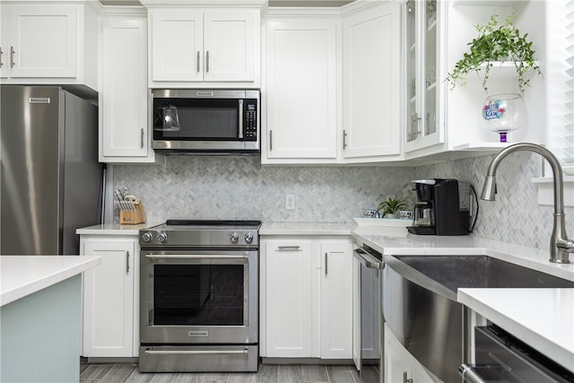 kitchen with backsplash, sink, white cabinets, and appliances with stainless steel finishes