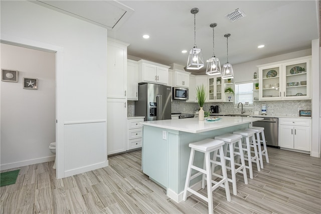 kitchen featuring white cabinets, appliances with stainless steel finishes, a center island, and light wood-type flooring