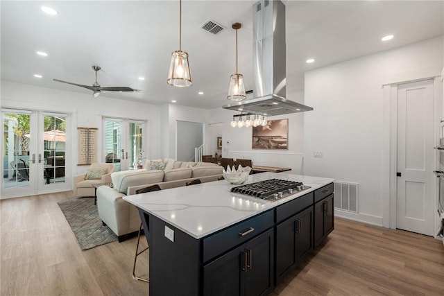 kitchen with visible vents, stainless steel gas cooktop, hanging light fixtures, and island range hood