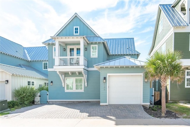 view of front of property with decorative driveway, an attached garage, board and batten siding, a standing seam roof, and metal roof