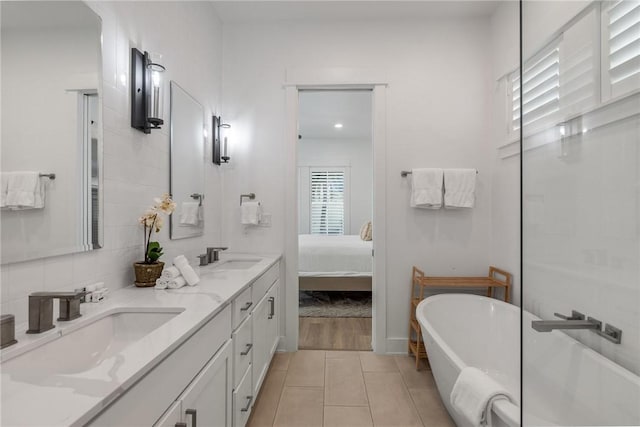 ensuite bathroom featuring tile patterned flooring, a soaking tub, a sink, and ensuite bath