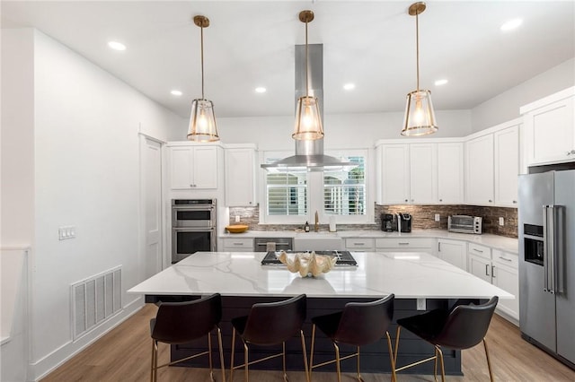 kitchen featuring light stone counters, a center island, visible vents, appliances with stainless steel finishes, and white cabinets