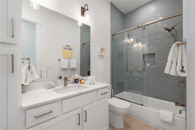 bathroom with bath / shower combo with glass door, vanity, toilet, and tile patterned floors