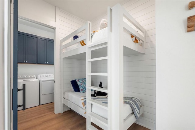 bedroom with wood walls, dark wood-type flooring, and washing machine and clothes dryer