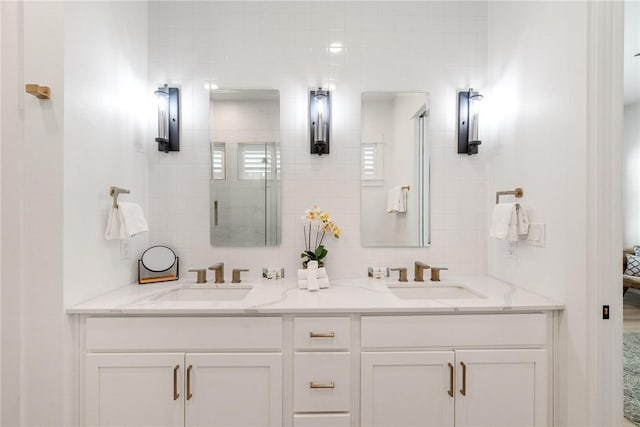 bathroom with a sink, a tile shower, and double vanity