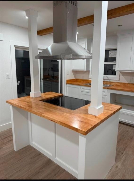 kitchen featuring white cabinetry, island exhaust hood, wooden counters, and black electric cooktop