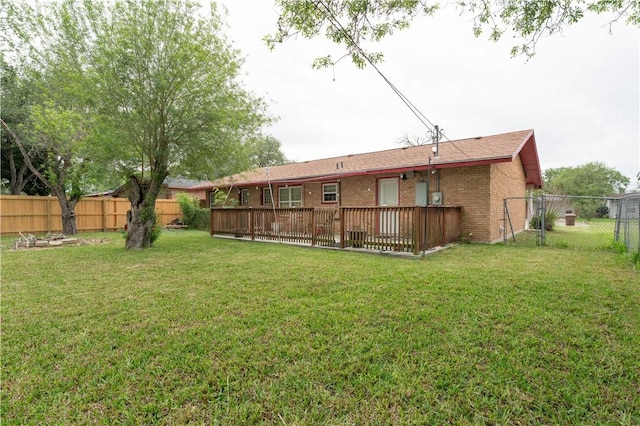 rear view of property featuring a yard, brick siding, and a fenced backyard