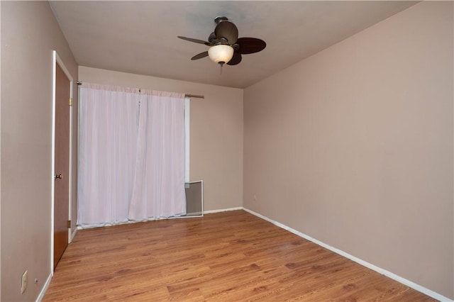 unfurnished room featuring a ceiling fan, light wood-style flooring, and baseboards