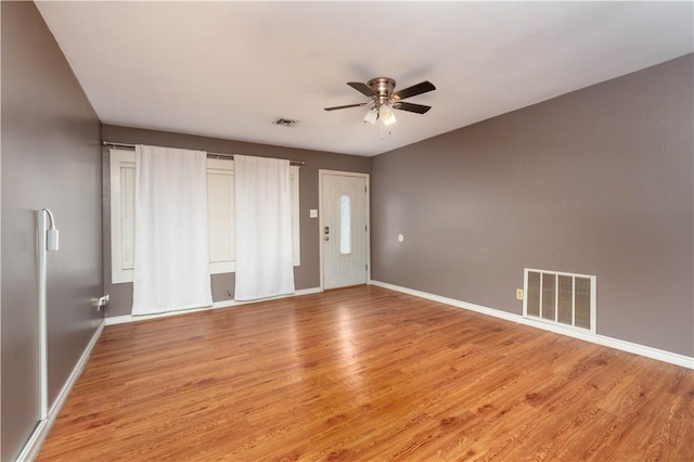 empty room featuring visible vents, ceiling fan, light wood finished floors, and baseboards