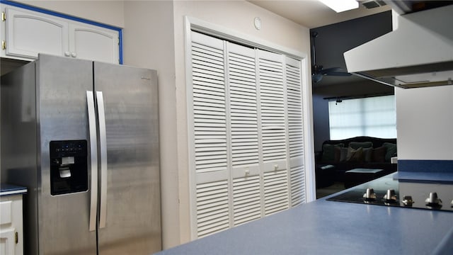 kitchen with white cabinets, stainless steel fridge, and range hood