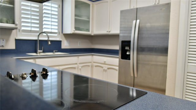 kitchen featuring black electric cooktop, white cabinetry, stainless steel refrigerator with ice dispenser, and sink