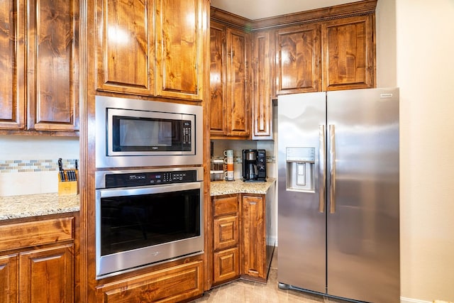 kitchen with stainless steel appliances, tasteful backsplash, and light stone countertops