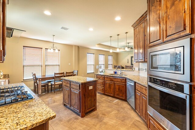 kitchen featuring sink, kitchen peninsula, appliances with stainless steel finishes, a center island, and pendant lighting