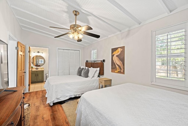 bedroom featuring ensuite bath, lofted ceiling with beams, light hardwood / wood-style flooring, a closet, and ceiling fan