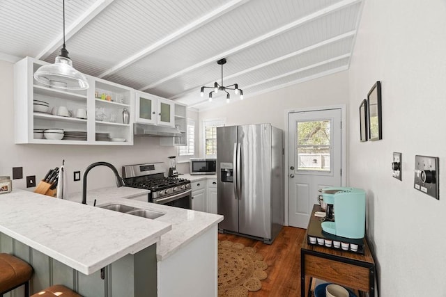 kitchen featuring kitchen peninsula, lofted ceiling with beams, pendant lighting, appliances with stainless steel finishes, and a kitchen breakfast bar