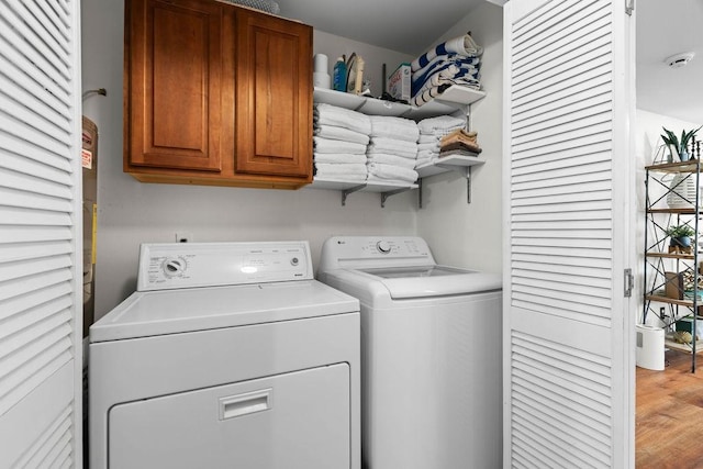 laundry room with wood-type flooring, separate washer and dryer, and cabinets