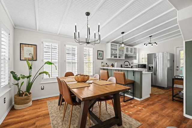 dining space with dark wood-type flooring, an inviting chandelier, and lofted ceiling with beams