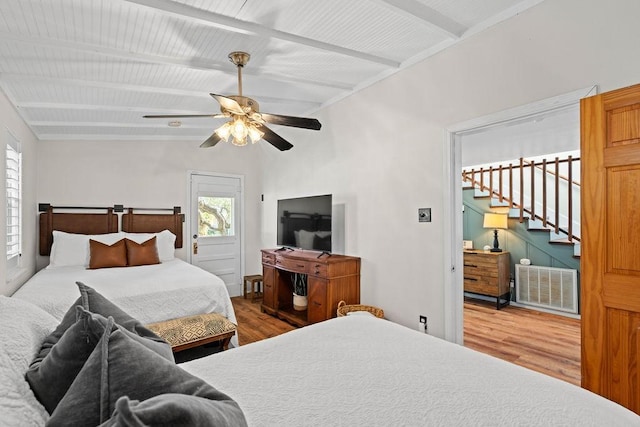 bedroom featuring ceiling fan, hardwood / wood-style flooring, and beamed ceiling