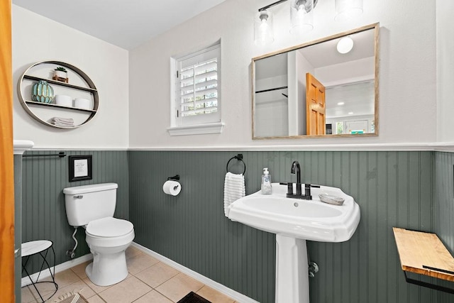 bathroom with toilet, wooden walls, tile patterned flooring, and sink