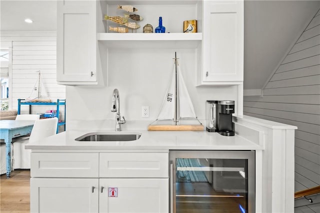 328 Coastline Dr, Port Aransas, TX 78373 - kitchen featuring open shelves, beverage cooler, wood walls, white cabinetry, and light countertops