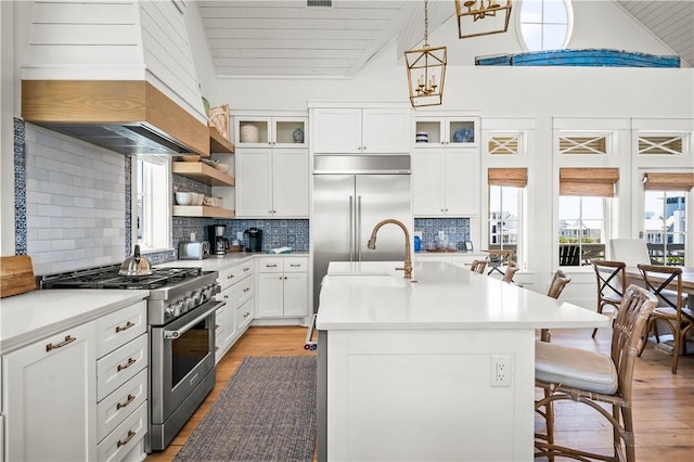 328 Coastline Dr, Port Aransas, TX 78373 - kitchen featuring high end appliances, premium range hood, light wood-type flooring, light countertops, and a breakfast bar area