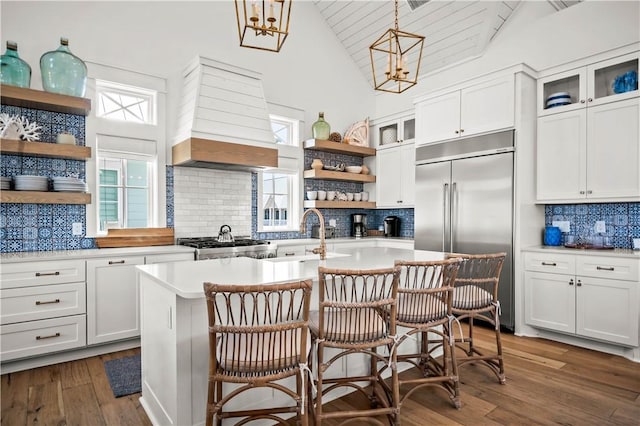 328 Coastline Dr, Port Aransas, TX 78373 - kitchen featuring stainless steel built in refrigerator, open shelves, custom exhaust hood, decorative backsplash, and an island with sink