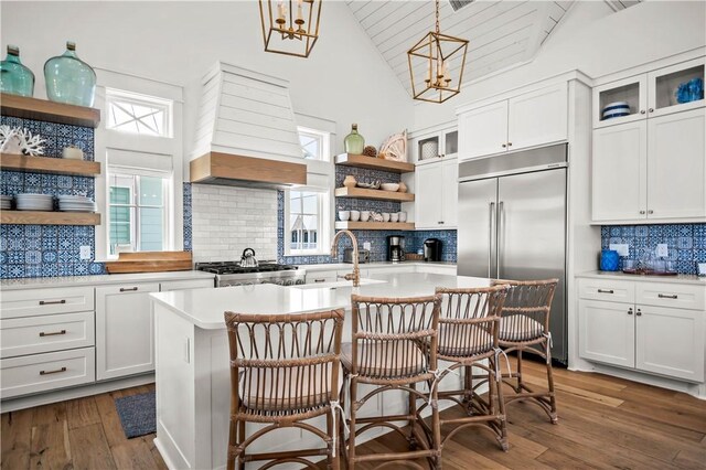 328 Coastline Dr, Port Aransas, TX 78373 - kitchen with stainless steel built in fridge, open shelves, premium range hood, tasteful backsplash, and an island with sink