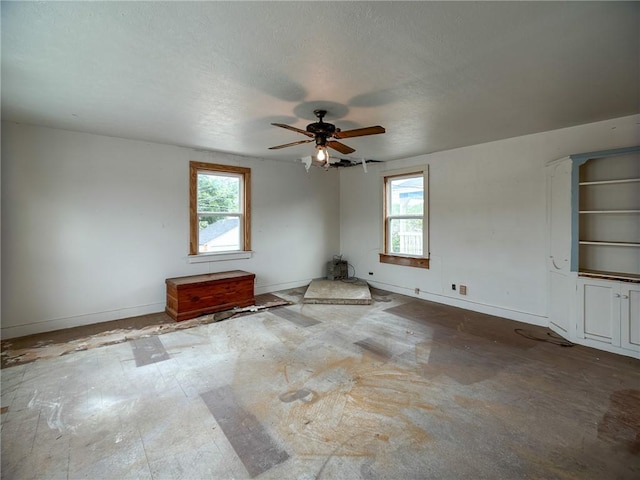 unfurnished room with plenty of natural light, baseboards, and a ceiling fan