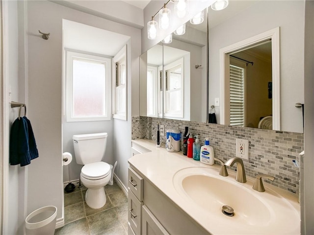 bathroom with tile patterned flooring, toilet, vanity, baseboards, and backsplash