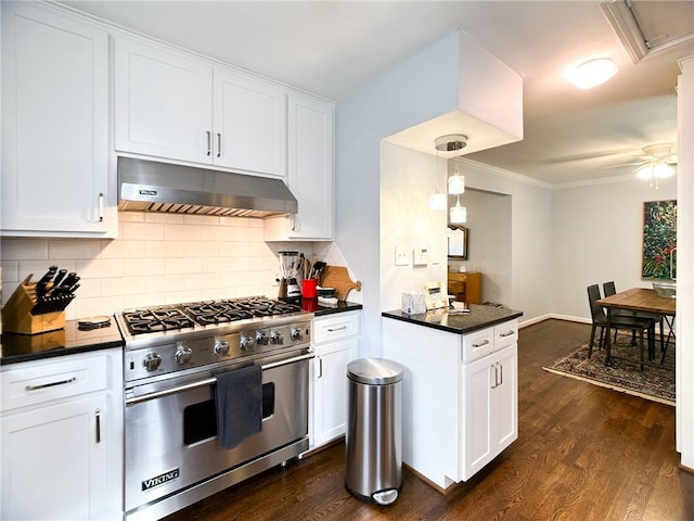 kitchen with designer stove, white cabinetry, hanging light fixtures, ventilation hood, and dark countertops