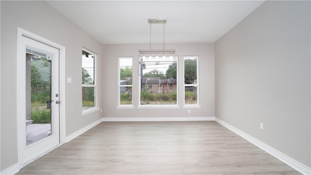 unfurnished dining area with a healthy amount of sunlight, light wood-type flooring, and an inviting chandelier