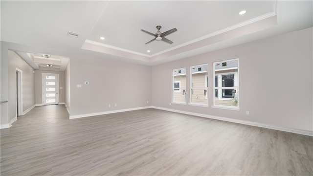 unfurnished room featuring light wood-type flooring, a raised ceiling, and ceiling fan